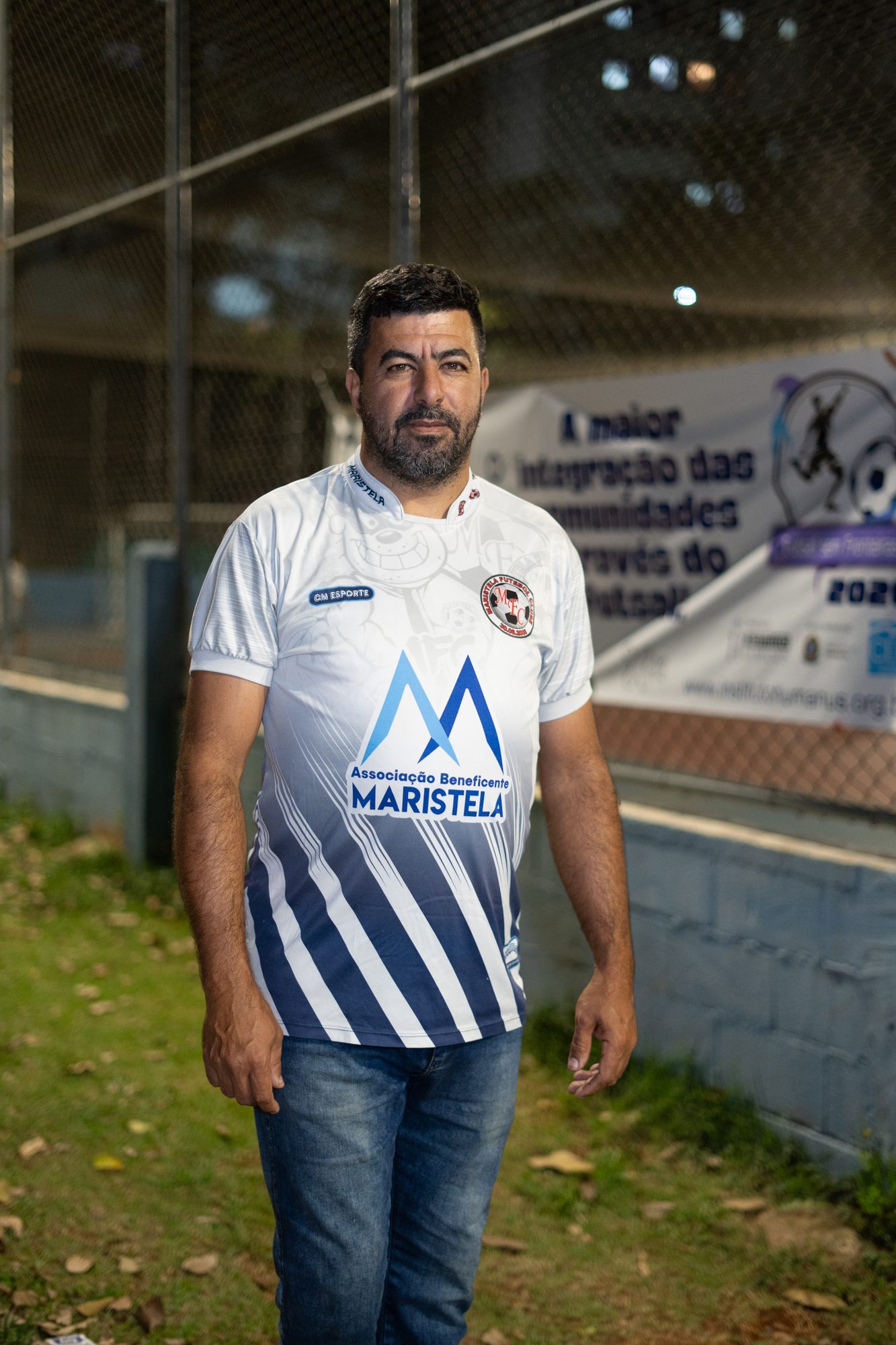 Homem com a camisa da Associação ao lado da faixa do evento